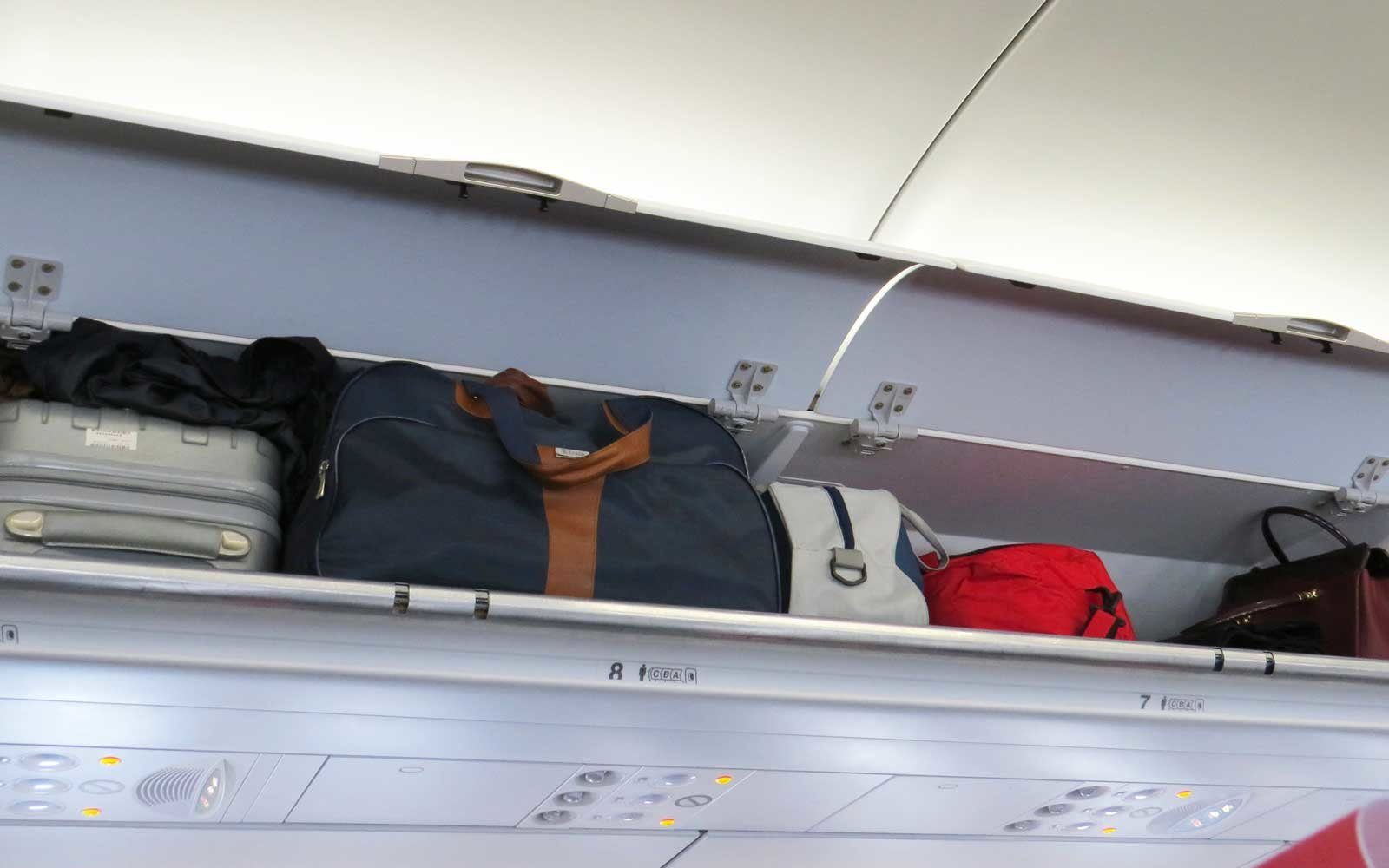 Сколько багажа в поезде. Багаж в салоне самолета. Полка для ручной клади в самолете. Багажная полка в самолете. Верхние полки в самолете.